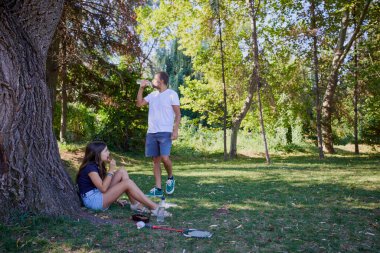 Baba ve kızı parkta birlikte zaman geçiriyorlar. Egzersiz yapıyor ve dinleniyorlar..