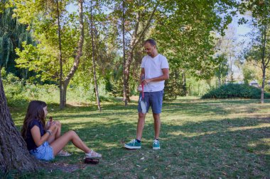 Baba ve kızı parkta birlikte zaman geçiriyorlar. Egzersiz yapıyor ve dinleniyorlar..