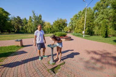 Baba ve kızı parkta birlikte zaman geçiriyorlar. Egzersiz yapıyor ve dinleniyorlar..