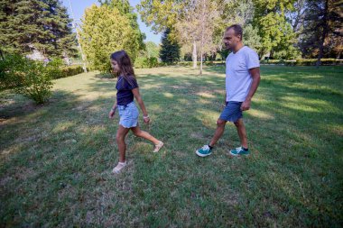 Baba ve kızı parkta birlikte zaman geçiriyorlar. Egzersiz yapıyor ve dinleniyorlar..