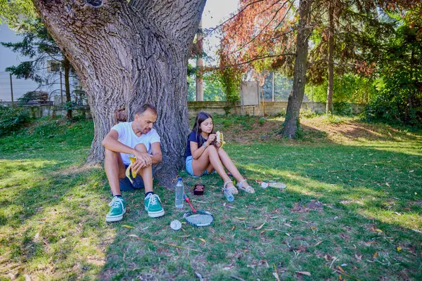 Baba ve kızı parkta birlikte zaman geçiriyorlar. Egzersiz yapıyor ve dinleniyorlar..