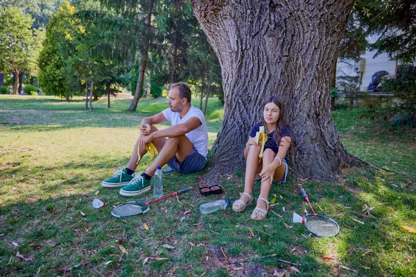 Baba ve kızı parkta birlikte zaman geçiriyorlar. Egzersiz yapıyor ve dinleniyorlar..