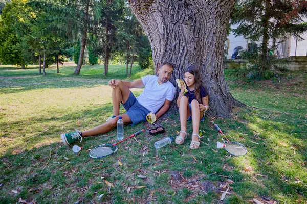 Baba ve kızı parkta birlikte zaman geçiriyorlar. Egzersiz yapıyor ve dinleniyorlar..