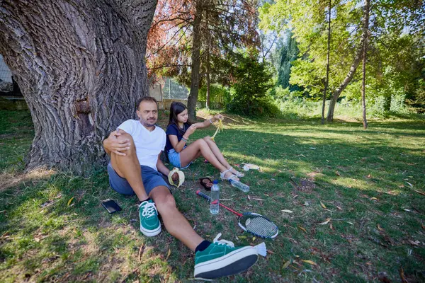 Baba ve kızı parkta birlikte zaman geçiriyorlar. Egzersiz yapıyor ve dinleniyorlar..