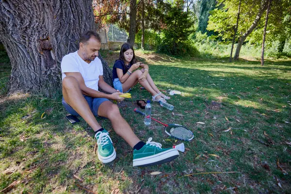 Baba ve kızı parkta birlikte zaman geçiriyorlar. Egzersiz yapıyor ve dinleniyorlar..