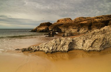 Cantabria, küçük dalgalı plaj Playa del Bocal, açık kum ve aşınmış kaya kayalıkları 