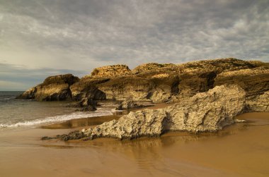 Cantabria, küçük dalgalı plaj Playa del Bocal, açık kum ve aşınmış kaya kayalıkları 