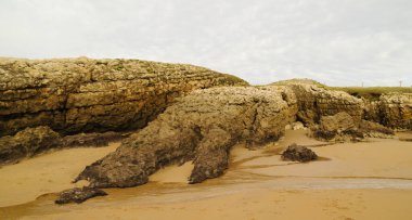 Cantabria, küçük dalgalı plaj Playa del Bocal, açık kum ve aşınmış kaya kayalıkları 