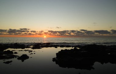 Lanzarote, Playa Honda 'da alçak gelgitte volkanik kayalarda küçük kaya havuzları, gün doğumu.