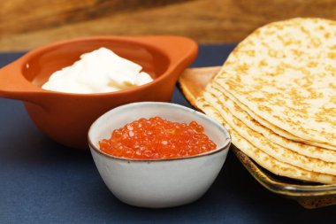 Küçük mavi bir kasede turuncu tuzlu somon yumurtası.