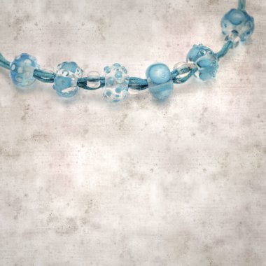 desenli eski kağıt arka plan, kare, mavi ve şeffaf cam boncuklardan oluşan basit bir kolye