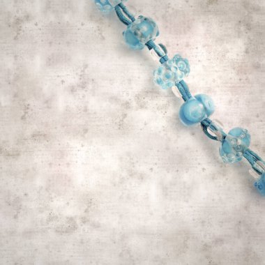 desenli eski kağıt arka plan, kare, mavi ve şeffaf cam boncuklardan oluşan basit bir kolye