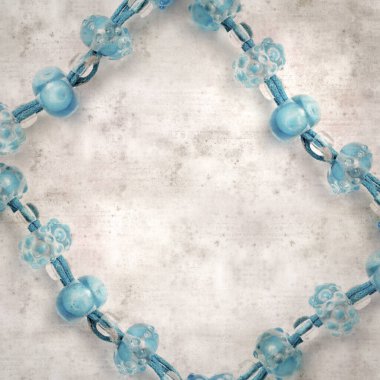 desenli eski kağıt arka plan, kare, mavi ve şeffaf cam boncuklardan oluşan basit bir kolye