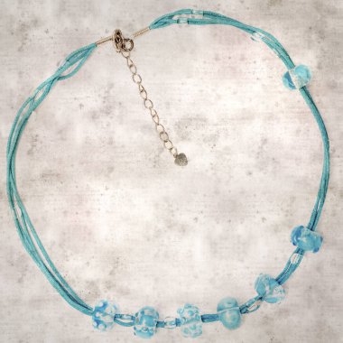 desenli eski kağıt arka plan, kare, mavi ve şeffaf cam boncuklardan oluşan basit bir kolye