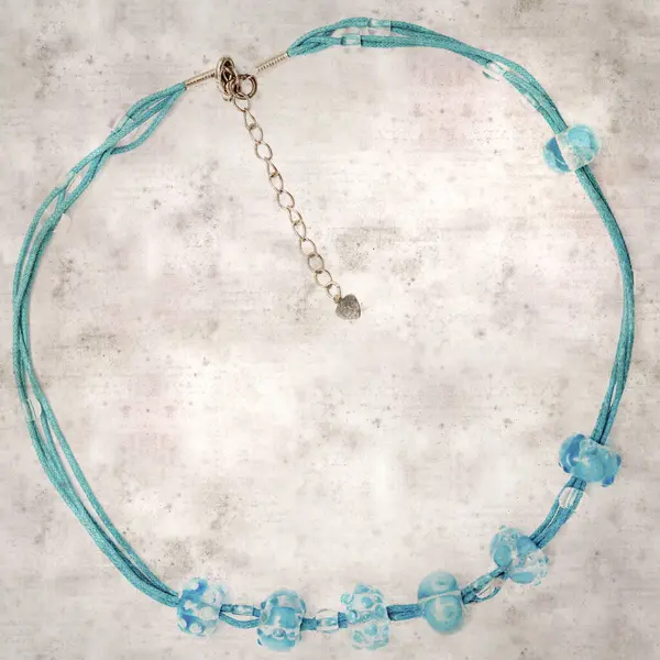 desenli eski kağıt arka plan, kare, mavi ve şeffaf cam boncuklardan oluşan basit bir kolye