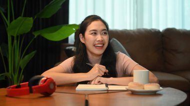 Günlük giysiler içinde ev ödevi yapan neşeli bir kadın ya da not defterine günlük randevu planlayan bir ajanda hazırlayan..