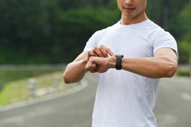 Sporcu koşudan sonra dinleniyor ve kalp atış hızını kontrol ediyor. Sağlıklı yaşam tarzı, egzersiz ve sağlık konsepti.