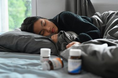 Hasta küçük kız yüksek ateş ve grip yüzünden battaniyenin altında yatıyor. Grip belirtileri, sağlık problemi konsepti.