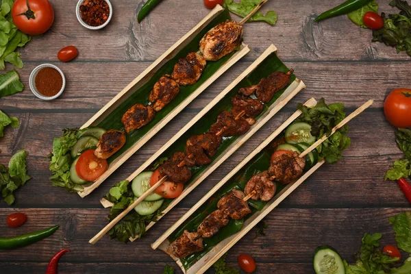 素朴な木製のテーブルの上に野菜に囲まれた竹の樽板に四川唐辛子とおいしい焼き肉 — ストック写真