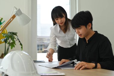 Mimarlar ekibi planları inceliyor, inşaat ofisindeki planlarla birlikte çalışıyor..