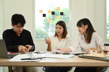 Mimarlar ve yönetici yönetici modern ofiste proje detaylarını tartışıyor.