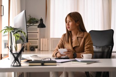 Hesap makinesi kullanan ve bilgisayar ekranında mali verileri kontrol eden hoş, genç bir ekonomist kadın.