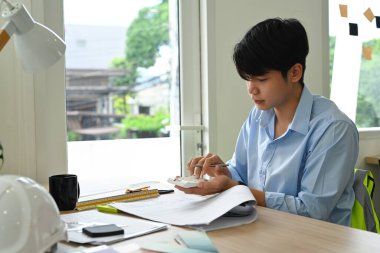 Yakışıklı Mimarlar planlara bakıyor, parlak modern ofiste inşaat planları üzerinde çalışıyor.. 