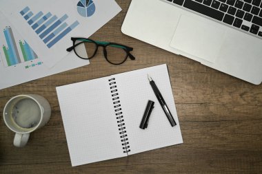 Boş not defteri, bardaklar, kahve fincanı ve laptop ahşap masada. Düz yatış, Üst Görünüm.