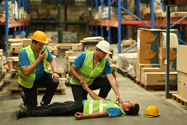 직원들 콘크리트 바닥에 의식을 채누워 동료들을 부상자들에게 응급처치를 있습니다 — 스톡 사진