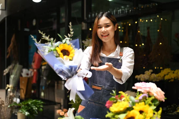 花の花束を持っている美しい女性の花屋の肖像画と彼女の花の店の前に立っている間 カメラに笑顔 — ストック写真