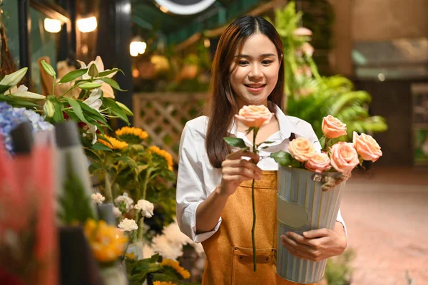 笑顔アジアの女性小企業経営者の花の店の前に立ってピンクのバラの花束を保持エプロンを身に着けて — ストック写真