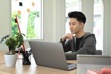Parlak modern ofiste tasarım projesi üzerinde çalışan konsantre yaratıcı adam..