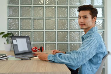 Yakışıklı Asyalı serbest yazar. Yaratıcı ofis stüdyosunda ses ve görüntülerle çalışıyor..