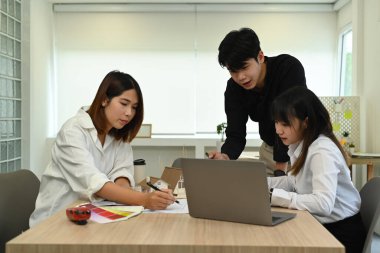 Mühendisler ya da mimarlardan oluşan bir ekip, modern ofiste yapılan toplantı sırasında ortak inşaat projesi üzerine beyin fırtınası yapıyorlar..