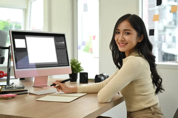 自信的女性照片编辑坐在有创意的工作场所的个人电脑前 对着相机微笑 — 图库照片