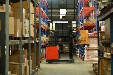 Karton kutularla dolu raflarla dolu büyük bir lojistik dağıtım deposunda forklift kamyonu..