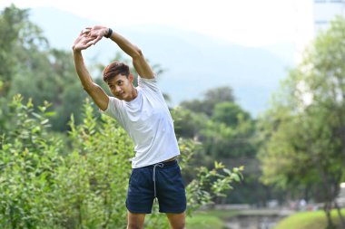 Genç sporcu adam sabah koşmadan önce kaslı kollarını esnetiyor. Fitness, spor ve sağlıklı yaşam tarzı kavramı.