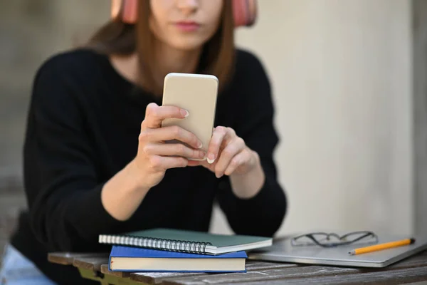 ヘッドフォンの入力テキストメッセージを身に着けている若い女性 携帯電話でオンラインチャット — ストック写真