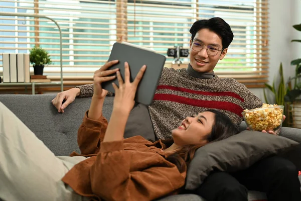 リラックスした若いアジアのカップルがポップコーンを食べ リビングルームで映画を見ています レジャー活動のコンセプト — ストック写真