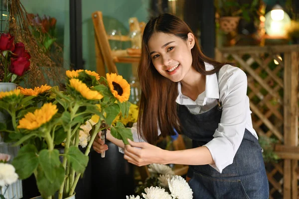 美しいひまわりの花束を持つ魅力的な女性花屋彼女の花の店の前に立って — ストック写真