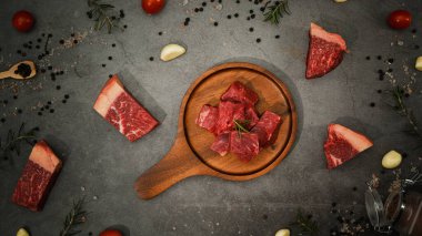 Biber, deniz tuzu, biberiye ve arkaplanda baharatla küp küp kesilmiş çiğ biftek eti..