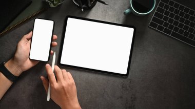 Elleri akıllı telefon ve tablet, boş ekran akıllı telefonu ve tableti olan üst kattaki ofis masasında. Yüksek kalite fotoğraf