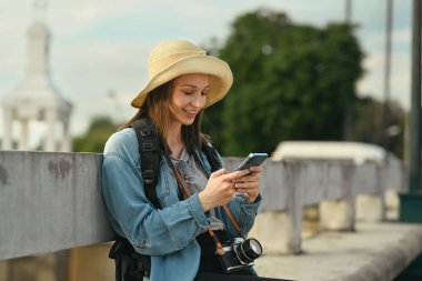 Akıllı telefon kullanan çekici bayan gezgin, tatil boyunca yeni maceraların tadını çıkarıyor..