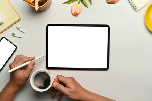 Flat lay digital tablet with blank screen, cup of coffee and blank notepad on white table. Top view with copy space.