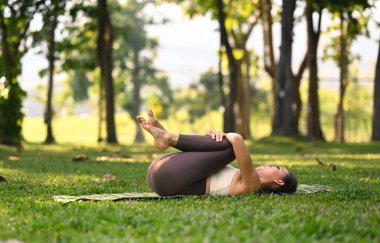 Meditasyoncu bir kadının yeşil çimlere poz verirken rüzgar ya da gaz çıkarması. Sağlıklı yaşam tarzı kavramı.