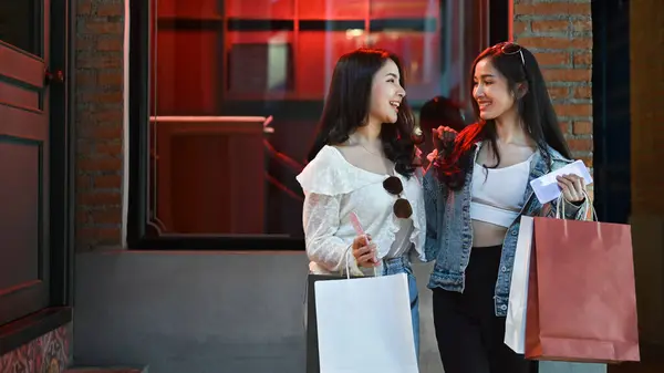 Alışveriş Torbalarıyla Konuşan Iki Şık Genç Kadın Şehrin Sokaklarında Vitrin — Stok fotoğraf