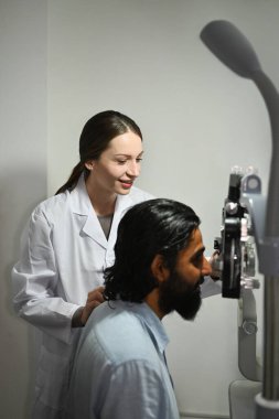 Genç Hintli adam göz doktoru kliniğindeki oto kırıcıyı kontrol ediyor. Göz sağlığı kontrolü ve göz doktoru konsepti.