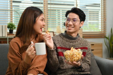 Evde patlamış mısırla televizyon izleyen genç mutlu çiftin görüntüsü. Boş zaman ve insan konsepti.