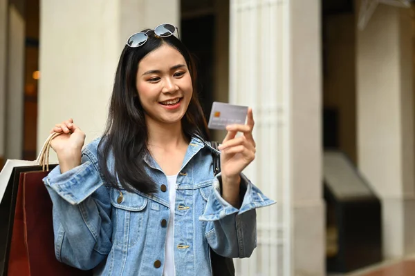 Attraktive Millennial Frau Mit Einkaufstaschen Und Blick Auf Kreditkarte Verkauf — Stockfoto
