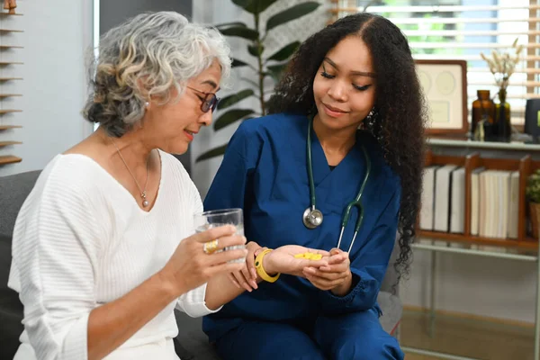 高齢女性への薬の投与量を説明する医療従事者や介護者 高齢者医療の概念 — ストック写真